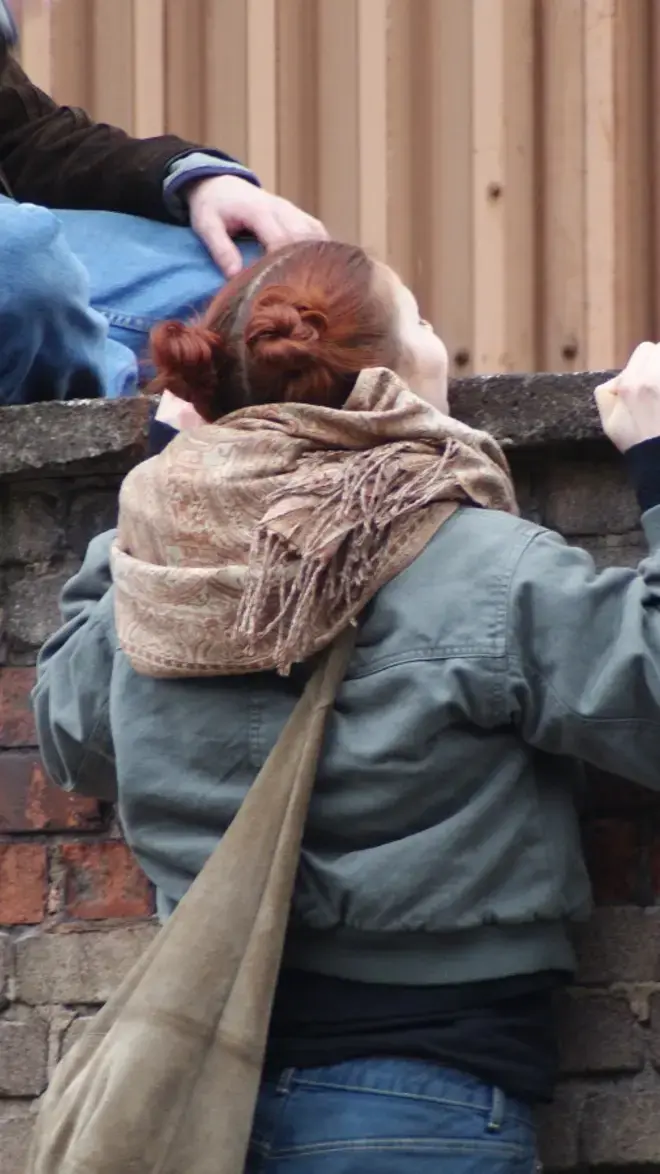 iArts studenten kijken over een muur.