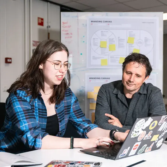 CMD - docent helpt leerling achter laptop