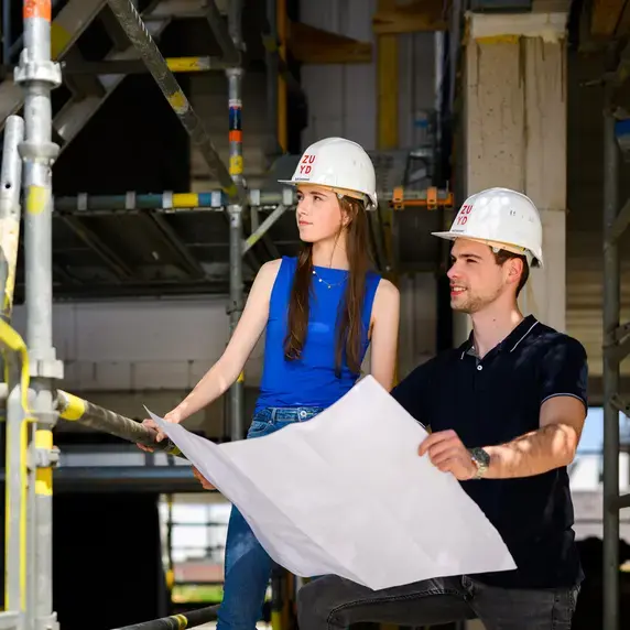 Built Environment - studenten met bouwtekening op steiger