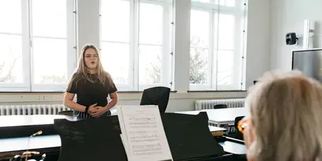 Docent Muziek - meisje zingt naast piano